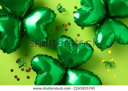 Happy Saint Patrick Day concept. Shamrock shaped balloons with confetti on green background