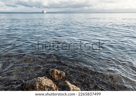 The shore of the reservoir. Sandy beach of a mountain lake with stones.