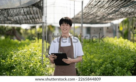 Young handsome Asian farm worker working in the farm while collect and write data on the document. Royalty-Free Stock Photo #2265844809