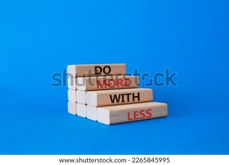 Do more with less symbol. Concept words Do more with less on wooden blocks. Beautiful blue background. Businessman hand. Business and Do more with less concept. Copy space.