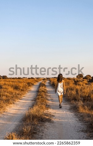 Lonely girl walking on a country road. Back view.