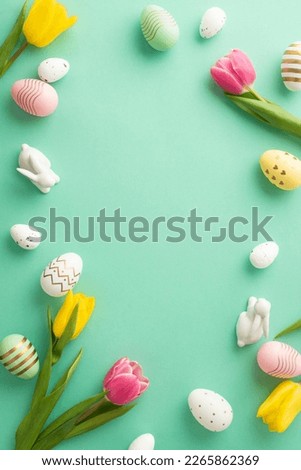 Easter celebration concept. Top view vertical photo of ceramic easter bunnies tulips and colorful easter eggs on isolated teal background with copyspace in the middle