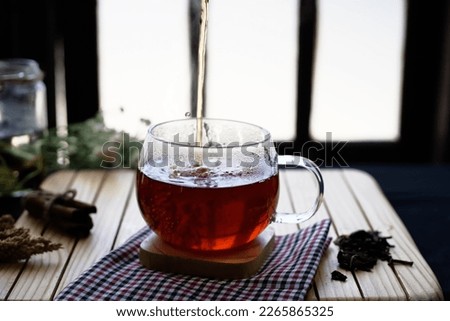 Herbal hot tea drink in glass with steam on old background in composition on table