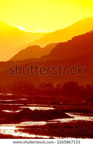 Sunset landscape with mountain layers and river waters. Golden hour in Greece. Saturated picture.