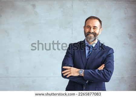 Portrait of happy mature businessman looking at camera. Multiethnic satisfied man with beard feeling confident at office. Successful middle eastern business man smiling in a creative office