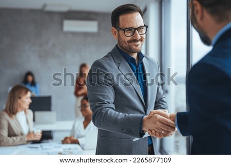 Portrait of cheerful young manager handshake with new employee. Business partnership meeting in office. Close up of handshake in the office. Mature businessman shake hands with a younger colleague Royalty-Free Stock Photo #2265877109