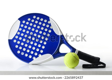 Padel racket and ball reflected on white table and white isolated background. Front view. Royalty-Free Stock Photo #2265892437
