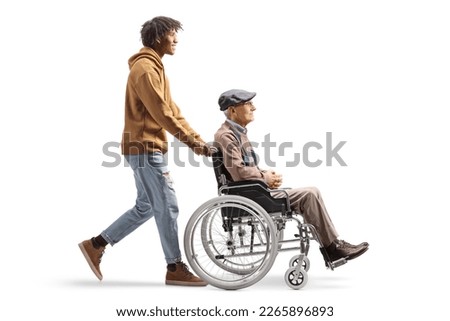 Full length profile shot of an african american young man pushing a senior in a wheelchair isolated on white background Royalty-Free Stock Photo #2265896893