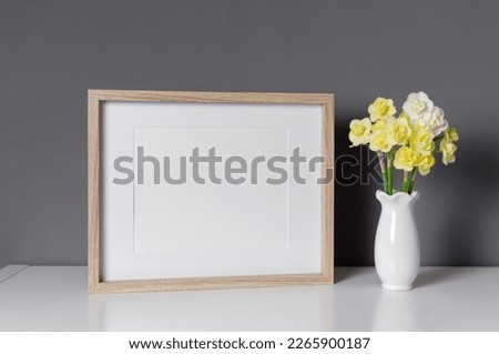 Wooden landscape frame mockup with flowers over grey wall, blank mockup for print presentation