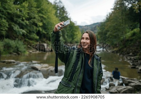 a tourist takes a selfie against the background of the mountain river