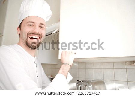 Young chef smiling while opening food storage door 