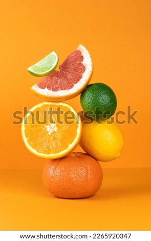 Balancing citrus fruits on the table. Pyramid of citrus fruits: grapefruit, lime, orange, lemon on orange background. 