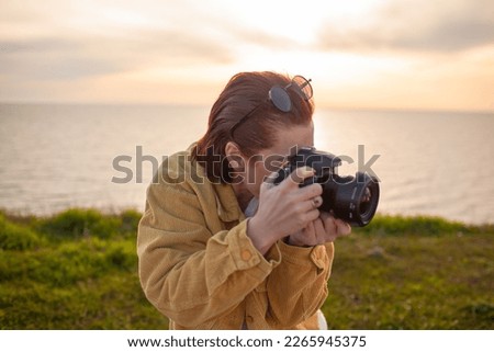 Redhair photographer holding camera and makes photos of nature