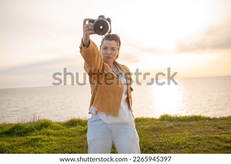 Redhair photographer holding camera and makes photos of nature