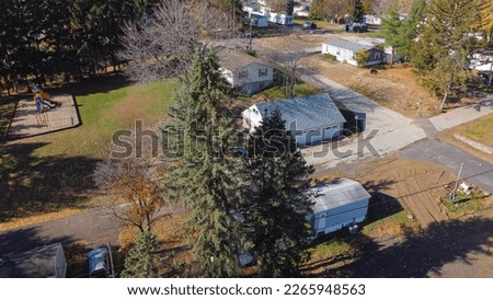 Mobile home in trailer park with playground and colorful fall foliage in Rochester, Upstate New York, USA. Aerial view low-income housing neighborhood with prefabricated house modular tiny units