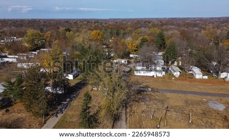 Construction site next to trailer park neighborhood with high density of prefabricated modular houses and colorful fall foliage in Rochester, Upstate New York, US. Aerial view low-income housing area