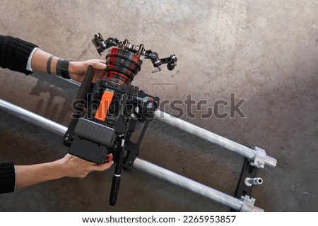 Male hands of a videographer roll and set up a professional movie camera on camera trolley and rails