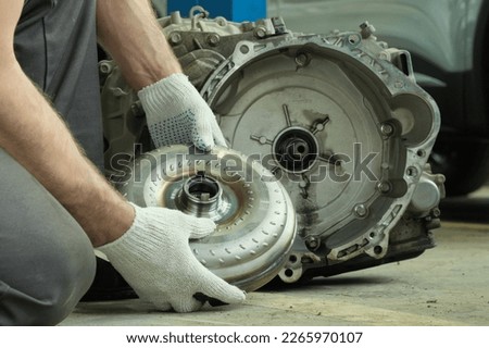 Repair and maintenance in a car service. Automatic transmission of a passenger car. An auto mechanic performs work on installing a torque converter. Royalty-Free Stock Photo #2265970107