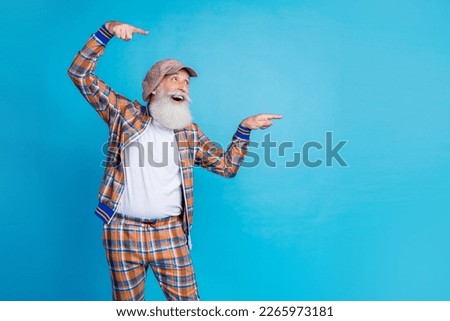 Photo of impressed excited man pensioner wear checkered costume looking pointing fingers empty space isolated blue color background