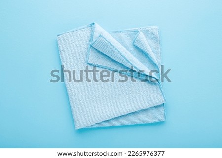 Folded dry soft microfiber rag for different surfaces wiping. Closeup. Light blue table background. Pastel color. Royalty-Free Stock Photo #2265976377