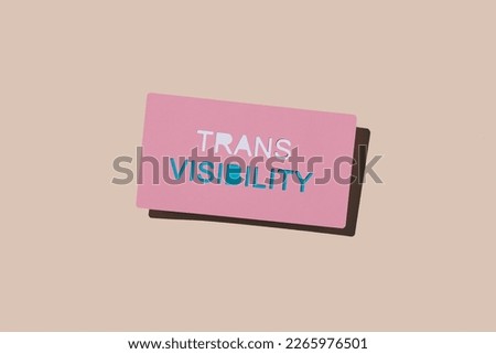 a pink cardboard sign with the text trans visibility on a pale pink background Royalty-Free Stock Photo #2265976501