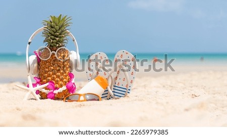 Summer in the party.  Hipster Pineapple Fashion in sunglass and listen music with sunblock and sandal on the sand beach beautiful blue sky background.  Fashion Summer Vacation  copy space for banner