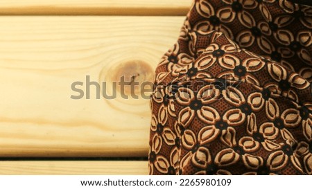 Indonesian batik cloth on a plank wood table. Ethnic fabric. Batik wallpaper.