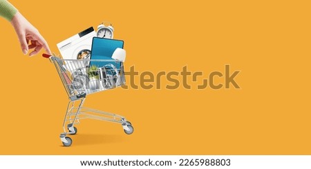 Woman pushing a small shopping cart full of household goods, appliances and electronics Royalty-Free Stock Photo #2265988803