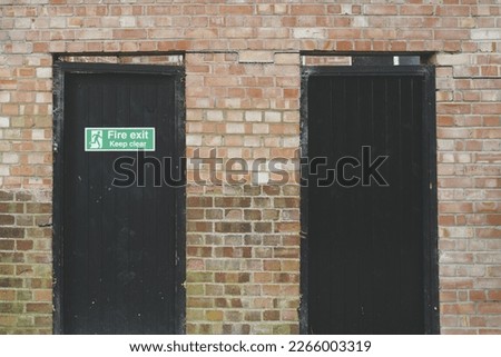 Abstract view of a pair of wooden doors leading to a retail shop's stock room. One door is designated as a Fire Door.