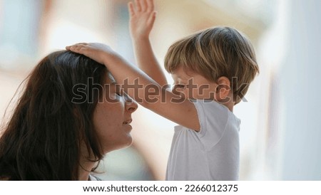 Parenting stress. Patient mother. Little boy hitting parent in the head with hand. Child misbehavior outside. Lifestyle real life stressful moment Royalty-Free Stock Photo #2266012375