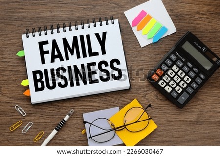 Family Business. on an open notepad text on a wooden background. calculator and sticker