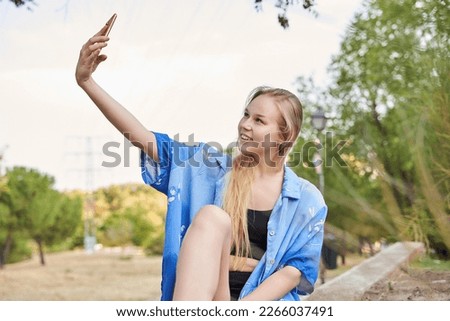 portrait of a blonde Caucasian woman taking a selfie with her smartphone