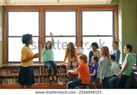 Education, learning and student with questions for teacher in middle school classroom. Library, scholarship group and girl learner raising hand to answer question, studying or help with black woman. Royalty-Free Stock Photo #2266048155
