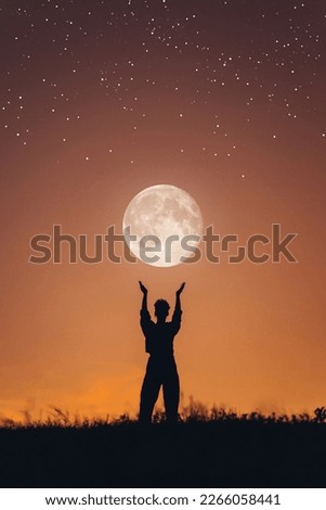 Fantastic photo of the silhouette of a girl holding the moon in her hands. Girl at sunset. Abstraction with starry sky. A person who dreams