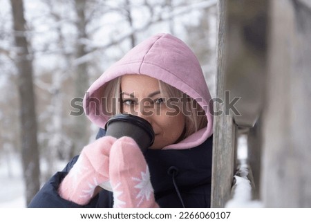 The girl enjoys the snow and drinks hot coffee. Winter fashion.
