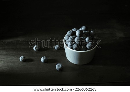 Dark food photography - close up bowl with blueberries on black background and dark table