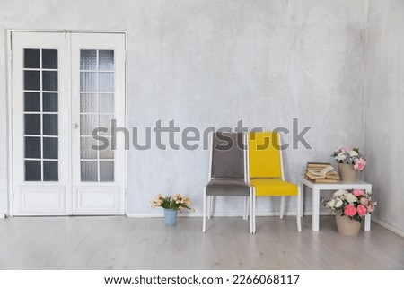 a grey and yellow chairs with coffee table with books and flowers