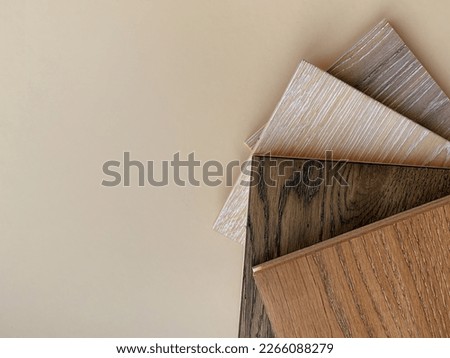 Engineered hardwood or laminate flooring swatch samples in various type of wood texture, isolated on beige background. A variety of shades of wood floor material- Top view Royalty-Free Stock Photo #2266088279
