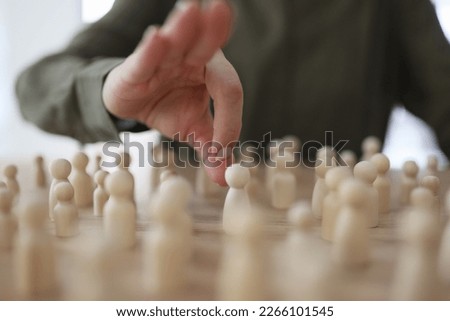 The female hand pushes wooden figures of men on the table, close-up. Concept pursuit, mobbing at work