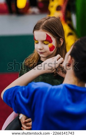 A professional make-up artist, woman artist paints face painting on her face with paints, children's makeup for a little girl, child. Photography, art, creativity concept, lifestyle.