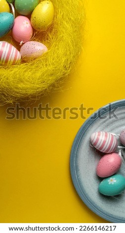 Colorful Easter eggs are laid out on a blue plate. Yellow Flat lay background.
