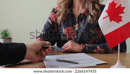 Canadian woman consular officer giving passport to male immigrant, work visa, citizenship. Visa Application online form immigration concept. Visa approval. Royalty-Free Stock Photo #2266147435