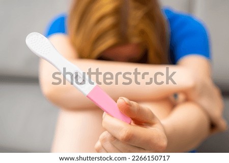 Disappointed woman holding a positive pregnancy test. Unexpected results. 