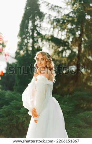 beautiful bride in a white delicate dress in the park at sunset. the concept of wedding fashion and organization of ceremonies in the fresh air.