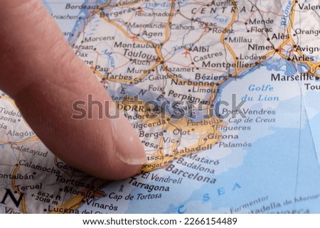 Finger pointing to Barcelona, Spain on a map with selective focus, background blur