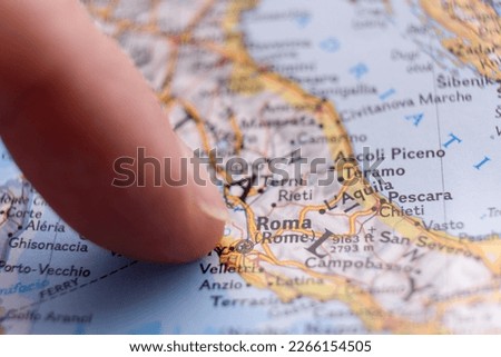 Finger pointing to Rome, Italy on detailed map with selective focus, shallow depth of field, background blur