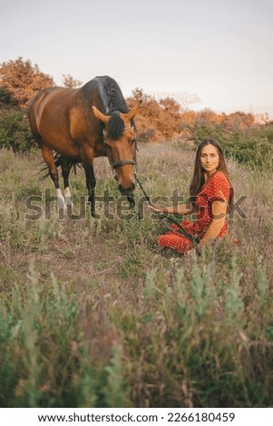 portrait of a beautiful long-haired girl in a red dress and a horse in a grove,	
