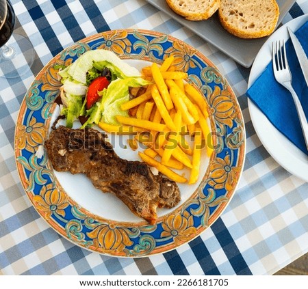 narrow slice of toasted entrecote is garnished with French fries and vegetables Royalty-Free Stock Photo #2266181705