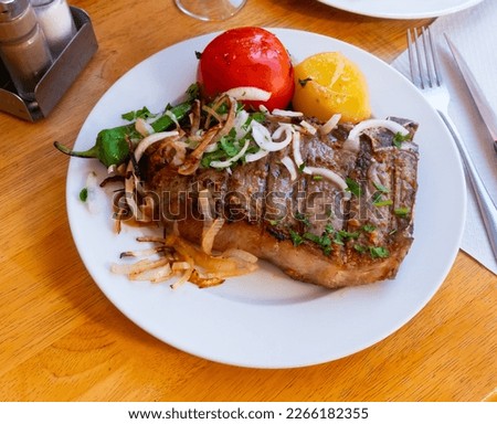 narrow slice of toasted entrecote is garnished with French fries and vegetables Royalty-Free Stock Photo #2266182355