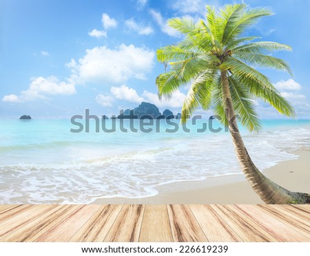 Summer holiday concept: Wooden table and coconut palm tree on tropic beach background